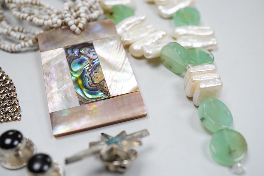 A collection of costume jewels, comprising: a floral coral and nephrite brooch; a composite opal triplet brooch designed as a turtle; a textured gilt metal ring set with hardstone fragments; a cultured pearl and chrysopr
